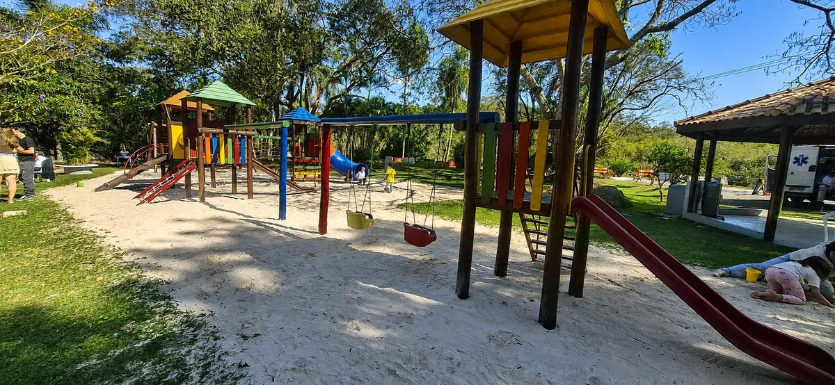 Playground do Patrimônio do Carmo, com brinquedos coloridos à sombra das árvores